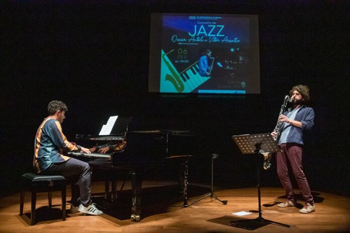 Das Bild zeigt die zwei Musiker auf einer Bühne mit Saxophon und Klavier.