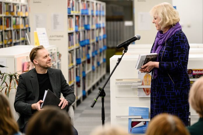 Das Bild zeigt die Übersetzerin des Buches und den Schauspieler Tambet Tuisk in einer Bibliothek