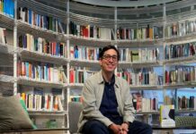 „Echtzeitalter“ in Quito, Bogotá und Medellín / Botschaft Bogota Das Bild zeigt Autor Tonio Schachinger sitzend vor einem vollen Bücherregal.