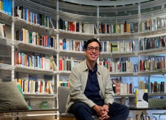 „Echtzeitalter“ in Quito, Bogotá und Medellín / Botschaft Bogota Das Bild zeigt Autor Tonio Schachinger sitzend vor einem vollen Bücherregal.