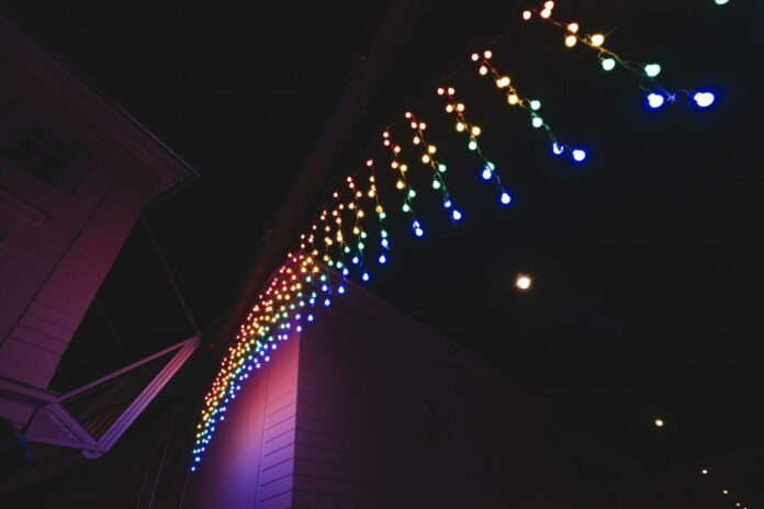 Das Bild zeigt eine Lichtinstallation aus kleinen Glühbirnen, die einem Regenbogen ähnelt.