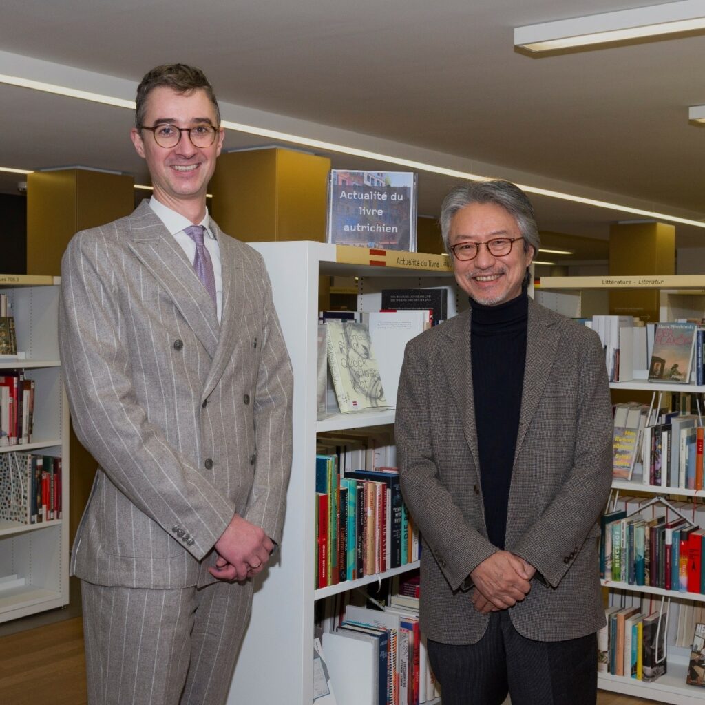 Das zweite Bild zeigt links Andreas Lins, Österreichischer Generalkonsul in Straßburg und rechts Alain Colas, Direktor der Bibliothèque nationale et universitaire in Straßburg vor Büchern österreichischer Autoren und Verlagen in Bücherregalen