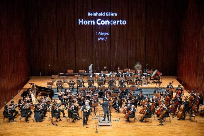 Das Bild zeigt den Hornisten Radovan Vlatkovic und das Thailand Philharmonic Orchestra auf der großen Bühne der Prince Mahidol Hall