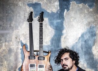 Persische Musik trifft Jazz / Kulturforum Paris Das Foto zeigt den Musiker Saleh Rozati am Boden sitzend vor einer Wand mit einer doppelhalsigen Gitarre.