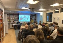 Feier des Bibliotheks-Relaunch / Kulturforum Paris Das Bild zeigt eine Veranstaltung in der Bibliothek mit sitzendem Publikum von hinten und den Vortragenden vorne auf einem Tisch.