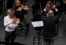 Tour von Yury Revich / Botschaft Santiago de Chile Das Bild zeigt den Geiger Yury Revich während der Interpretation des Paganini Violinkonzertes beim pizzicato und rechts von ihm den Dirigenten des chilenischen Nationalorchesters beim Dirigieren. Dahinter sieht man zwei Streicher aus dem Orchester.