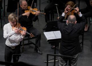 Tour von Yury Revich / Botschaft Santiago de Chile Das Bild zeigt den Geiger Yury Revich während der Interpretation des Paganini Violinkonzertes beim pizzicato und rechts von ihm den Dirigenten des chilenischen Nationalorchesters beim Dirigieren. Dahinter sieht man zwei Streicher aus dem Orchester.