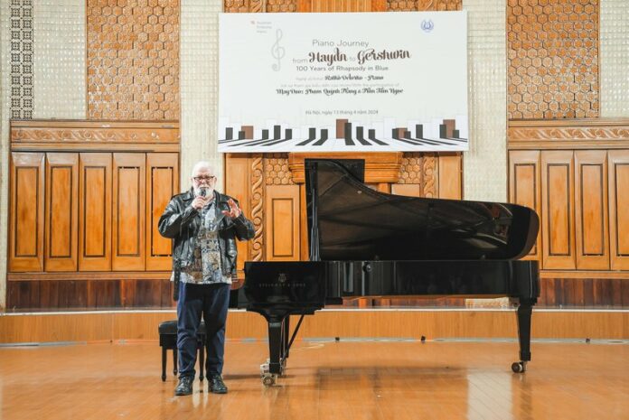 Das Bild zeigt Ratko Delorko neben einem Flügel im Kammermusiksaal der Musikakademie.