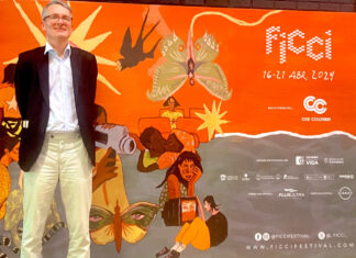 63. Filmfestival Cartagena / Botschaft Bogota Das Bild zeigt Gesandten Alexander Springer von der ÖB Bogota, hinter ihm eine orangefarbene Plakatwand mit dem Logo des Internationalen Filmfestivals von Cartagena und einigen Illustrationen.