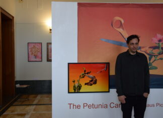 Ausstellung „The PETUNIA CARNAGE“/ Klaus Pichler / Kulturforum Rom Das Bild zeigt den Fotograf Klaus Pichler bei der Ausstellungseröffnung von „THE PETUNIA CARNAGE“ im Atrium vom Österreichischen Kulturforum Rom. Er befindet sich vor einem seiner Werke, worauf man eine Schere sehen kann, welche eine orange, genmanipulierte Petuniensorte umschlingt und dabei auf ihre weltweite Zerstörung hingewiesen wird.