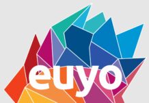 European Union Youth Orchestra / Kulturforum Brüssel Das Bild zeigt das Logo des Orchesters. Das Bild besteht aus abstrakten, bunten Formen, die von Gelb und Orange in der linken unteren Ecke bis zu Rot, Lila und schließlich Blau in der rechten oberen Ecke reichen. In der Mitte steht das Wort „euyo“ in weißer Schrift.