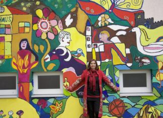 Workshop / Kulturforum Zagreb Das Bild zeigt die Künstlerin Lisa Wolf vor einer bunt bemalten Wand