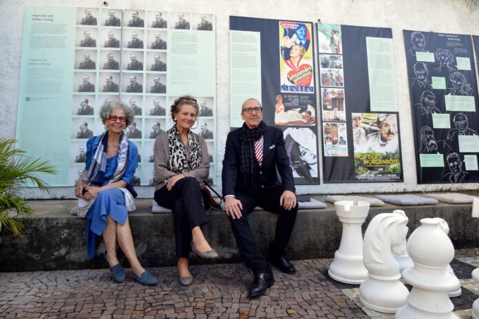 Das Bild zeigt Botschafter Dr. Stefan Scholz sowie Kristina Michahelles und Ruth Freihof sitzend vor Paneelen der Ausstellung „Stefan Zweig. Weltautor“ auf der Terrasse der Casa Stefan Zweig in Petrópolis