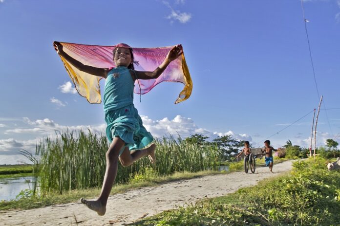 Kushal Gangopadhyay: Happy Leap, India Kinder spielen an einem Nachmittag in einem Dorf in Westbengalen in Indien. Das Leben am Land ist in Indien langsam und ruhig, und die Kinder haben die Möglichkeit, ihre Kindheit zu genießen.