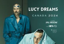 Lucy Dreams Canada Tour / Kulturforum Ottawa Das Bild zeigt das Poster von Lucy Dreams. Im Vordergrund sind die Bandmitglieder in einer Nahaufnahme zu sehen, wobei einer steht und der andere sitzt. Der Hintergrund ist in einem dunklen türkisblauen Grün gehalten. Die Bandmitglieder tragen ähnliche Farbpaletten für Make-up und Outfits: Der stehende Musiker trägt einen langen, dunkeltürkisen Ledertrenchcoat, während der sitzende Musiker einen übergroßen, hellblau-türkisen Blazer trägt. Der Titel „Lucy Dreams“ ist in weißer Schrift auf dem Poster abgebildet. Unterhalb des Titels sind die Logos der Sponsoren zu sehen.