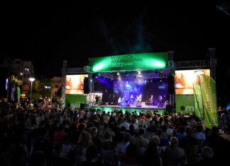 Mitrovica Int. Jazz Days 2024 / Botschaft Pristina Das Bild zeigt den Auftritt einer mehrköpfigen Jazz-Band mit vollem Publikum.
