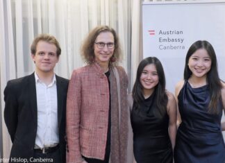 Trio Alpenrose / Botschaft Canberra Das Bild zeigt Botschafterin Kögler mit dem Trio Alpenrose vor einem Logo der Österreichischen Botschaft Canberra