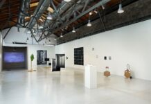 Ausstellung „Looking Elsewhere Being There” / Botschaft Ankara Das Bild zeigt die in weiß gehaltene Ausstellungshalle mit zahlreichen Ausstellungsstücken. Bilder, Fotografien, sowie Skulpturen