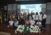 Wohnbau in Amazonien / Botschaft Brasilia Das Bild zeigt eine Gruppe von 23 Personen, vor allem brasilianische Studierende, auf einer Bühne mit der Ankündigung der Veranstaltung im Hintergrund auf einer Leinwand eingeblendet.