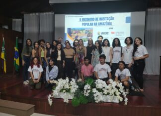 Wohnbau in Amazonien / Botschaft Brasilia Das Bild zeigt eine Gruppe von 23 Personen, vor allem brasilianische Studierende, auf einer Bühne mit der Ankündigung der Veranstaltung im Hintergrund auf einer Leinwand eingeblendet.