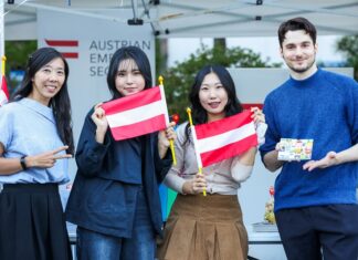 Europäischer Sprachentag / Botschaft Seoul Vier Personen die vor dem Österreichischer Stand am "Tag der europäischen Sprachen" 2024 stehe. Zwei der Personen halten kleine Österreich Flaggen.
