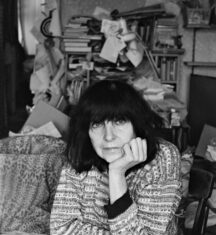 Ich bin so FLEUR dasz nichts mehr geht / Kulturforum Berlin Das Bild zeigt die österreichische Schriftstellerin Friederike Mayröcker mit schulterlangem, dunklem, Haar und einem ernsten Gesichtsausdruck. Sie stützt ihren Kopf nachdenklich mit einer Hand und schaut direkt in die Kamera. Die Aufnahme ist in Schwarz-Weiß gehalten, wodurch die Gesichtszüge und die Struktur ihres Pullovers besonders betont werden. Die Hintergrunddetails sind unscharf und dezent, sodass der Fokus ganz auf ihrem Gesicht liegt.