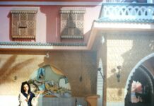 A Sea of Stories / Kulturforum Istanbul Das Foto zeigt das Werk „A Sea of Stories“ von Lisl Ponger. Die orientalische Szene zeigt vor einem Haus einen schlafenden Mann im Stuhl, vor sich eine Wasserpfeife. Hinter ihm sitzt eine dunkelhaarige Frau am Divan, rechts von ihm ein Mann mit einer Wasserpfeife in der Hand