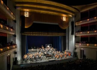 Anton Bruckners Symphonie der Hoffnung / Kulturforum Teheran Das Bild zeigt die Teheraner Vahdat Halle und das 90-köpfige AISO Symphonieorchester. Links und rechts über der Bühne das Bild von Ajatollah Ali Chamenei