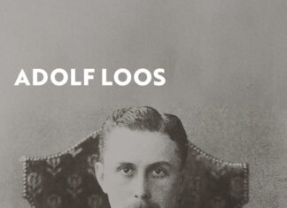 Adolf Loos Ausstellung in Uruguay / Botschaft Buenos Aires Das Bild zeigt das Ausstellungsplakat, auf welchem ein Porträt des Architekten Adolf Loos zu sehen ist. Er sitzt auf einem hohen Lehnstuhl, hat einen Anzug und Krawatte an, die Hände auf dem Schoss ineinander verschränkt und starrt streng in die Kamera. Er ist auf diesem Bild noch jung.