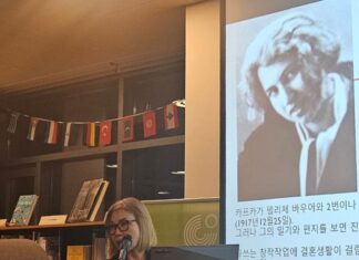 Kafkas letzte Reise / Botschaft Seoul Das Bild zeigt Professor Dr. Jang Eun-soo von der Hankuk University of Foreign Studies (HUFS) beim wissenschaftlichen Einführungsvortrag im Goethe Institut Korea. Sie steht vor einer Bücherwand und einem projizierten Bild von Kafkas Lebensgefährtin Dora Diamant