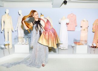 The Future of Living / Kulturforum Brüssel Das Bild zeigt die Designerin Flora Miranda, die stolz einige ihrer Kreationen (hauptsächlich Kleider) vorführt, während sie ihr Haar zurückwirft.