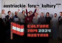 Culture Jam: Austria 2024 / Kulturforum Warschau Das Bild zeigt eine Gruppe junger Menschen, die auf einer Bühne stehen, mit einigen Personen, die Zertifikate in den Händen halten. Im Hintergrund ist eine weiße Wand mit dem Schriftzug „austriackie forum kultury waw“ zu sehen, der in schwarzer Schrift geschrieben ist. Die Personen wirken fröhlich und feiern gemeinsam ihren Erfolg, einige heben die Hände triumphierend in die Luft. Im Vordergrund befindet sich das Logo des Events „Culture Jam: 2024 Austria“, gestaltet im Retro-Pixel-Art-Stil, mit einer rot-weiß-roten Fahne und der Schrift in auffälligen roten und grauen Farben. Die Szene wird von einem Publikum beobachtet, das teilweise von hinten zu sehen ist.