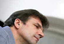 Konzerte zum Gedenken an die Opfer des Holocaust / Kulturforum Paris und Kulturforum Brüssel Das Bild zeigt ein Porträt des österreichischen Baritons Wolfgang Holzmair. Er trägt ein graues Hemd und hebt die Hand zum Takt.