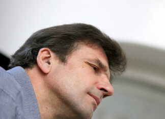 Konzerte zum Gedenken an die Opfer des Holocaust / Kulturforum Paris und Kulturforum Brüssel Das Bild zeigt ein Porträt des österreichischen Baritons Wolfgang Holzmair. Er trägt ein graues Hemd und hebt die Hand zum Takt.