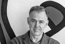 „Circularchitecture – Regeneratives Bauen“ / Kulturplattform Arabischer Raum Das Schwarz-Weiß-Bild zeigt den Vortragenden Thomas Romm, der vor einer Wand mit gekreuzten Armen steht.