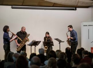 Konzert „Spectrum Saxophonquartett“ / Kulturforum Bratislava Das Bild zeigt das lächelnde „Spectrum Saxophonquartett“ vor einer weißen Wand. Alle sind dunkel angezogen und halten ihre Instrumente.