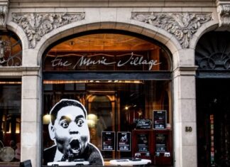 Jazz-Begegnungen im The Music Village / Kulturforum Brüssel Das Bild zeigt die Fassade des Konzertsaals The Music Village. Auf einem großen Fenster ist ein riesen Schwarz-Weiß-Aufkleber mit einem schockiert dreinschauenden Mann zu sehen.