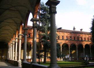 Gedenken an Rudolf Haller / Kulturforum Mailand Das Bild zeigt den Hof von di Universität Milano Università degli Studi. Auf der linken Seite des Bilds sind Gänge mit hohen Bögen ersichtlich, während die rechte Seite mit dem Garten einen starken Kontrast bildet.