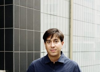 Jaipur-Literaturfestival / Kulturforum New Delhi Das Bild zeigt den Autor Tonio Schachinger, wie er vor einem Gebäude steht. Seine Hände stecken in seinen Hosentaschen und er trägt eine weiße Jeans mit einem dunkelblauen kurzärmligen Hemd.