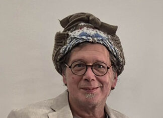 Kunst im Gespräch – neue Podcastserie Das Bild zeigt den Künstler Franzobel. Er hat einen bunten Turban auf und lacht in die Kamera.