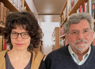 Verena Mermer & Geoff Howes / Kulturforum Washington Das Bild zeigt Verena Mermer und Geoff Howes, sie blicken gerade in die Kamera, hinter ihnen eine Bibliothek.