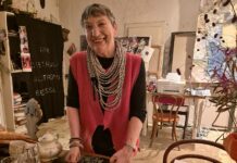 Kunst im Gespräch – Podcastserie Es ist die Künstlerin Linda Waber zu sehen. Sie steht in ihrer Küche und lächelt. vor ihr liegen Orangen.