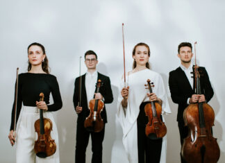 Javus Quartett / Kulturforum Prag Das Bild zeigt vier Mitglieder des Quartetts stehend und nach vorne oder nach oben blickend. Sie halten ihre Streichinstrumente in der linken, ihre Bögen in der rechten Hand. Alle Bögen sind nach oben gerichtet.