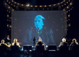 Die letzten Zeugen in Akko / Kulturforum Tel Aviv Das Bild zeigt fünf österreichische Holocaust-Überlebende von hinten und Schoschana Rabinovici auf einem Screen.