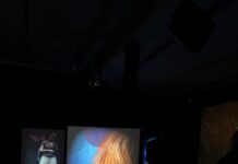 Techne Ausstellung / Botschaft Pristina Das Bild zeigt den Ausstellungsraum inklusive drei Bildschirme mit Ausschnitten aus den Videospielen.