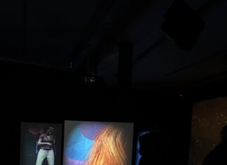 Techne Ausstellung / Botschaft Pristina Das Bild zeigt den Ausstellungsraum inklusive drei Bildschirme mit Ausschnitten aus den Videospielen.