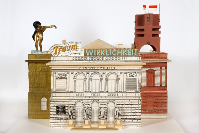 altKFLondon Das Bild zeigt ein Modell der Künstlerhausfassade in Wien 1985 von Hans Hollein. In Großbuchstaben die Worte „Traum und Wirklichkeit“ auf dem Gebäude. Auf der Fassade selbst findet sich der Schriftzug „Wien 1870-1930.