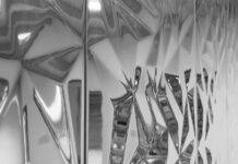 Adding Depth – Vertiefung / Kulturforum Istanbul Das Bild zeigt eine spiegelnde, geometrisch strukturierte Oberfläche mit facettierten Formen und Lichtreflexionen.