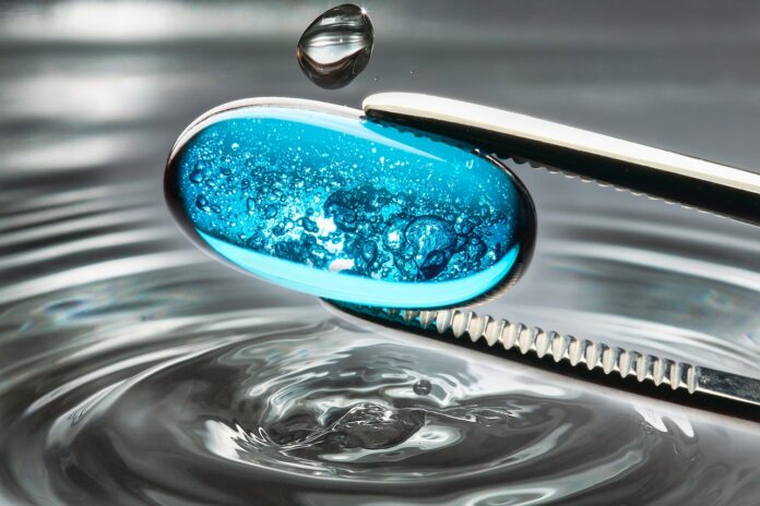 Bild: Pixabay Das Bild zeigt einen blauen Tropfen, der von einer Zange gehalten wird, vor graugefärbtem Wasser.