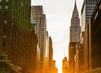 Manhattanhenge Jazz Lounge / Kulturforum New York Sonnenuntergang zwischen den Hochhäusern Manhattans: Die untergehende Sonne scheint genau entlang der Ost-West-Straße und taucht die Szene in goldenes Licht – ein Naturphänomen, das als „Manhattanhenge“ bekannt ist.